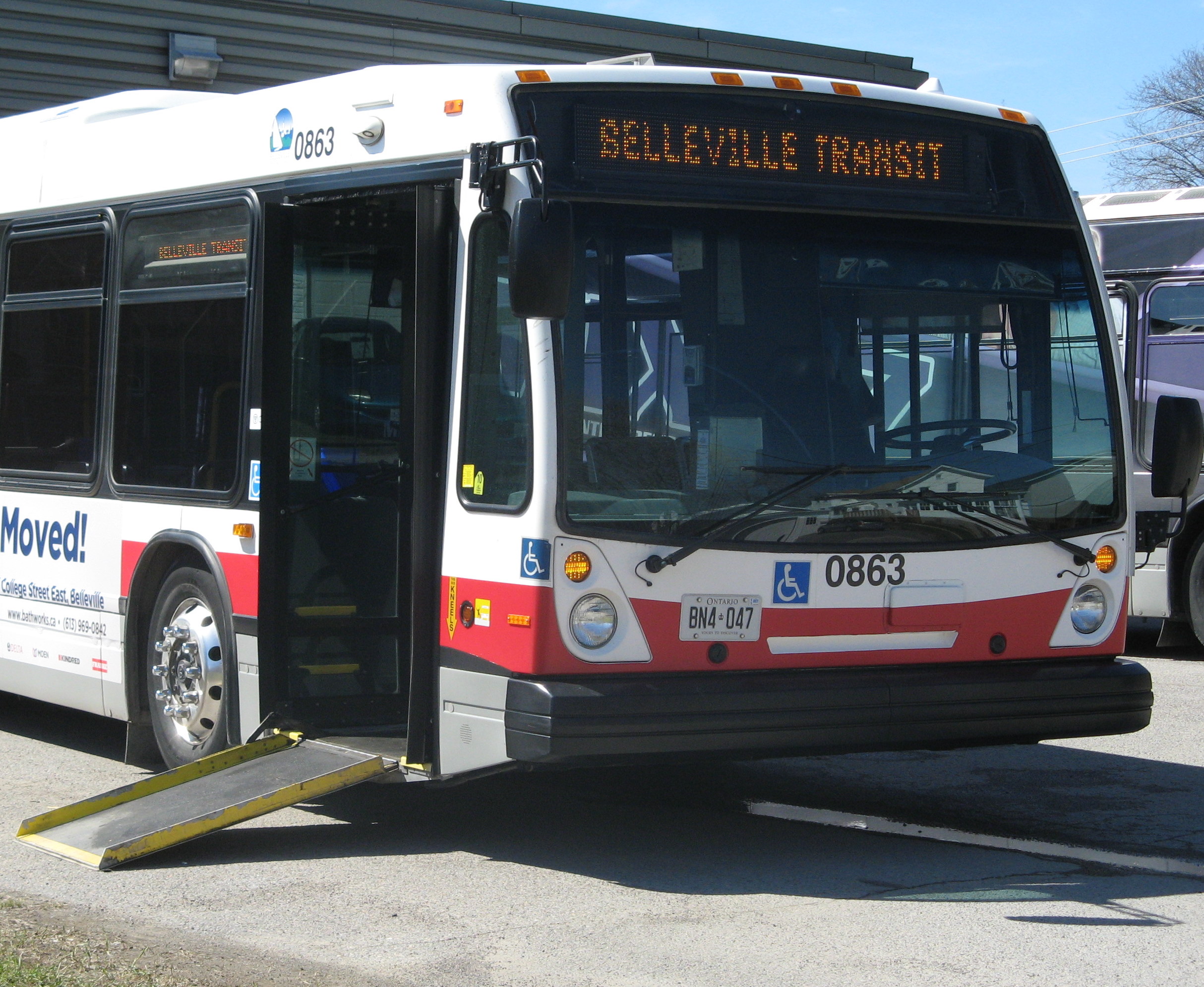 a conventional transit bus from Belleville Transit lowers the front entrance and deploys the ramp for easier boarding