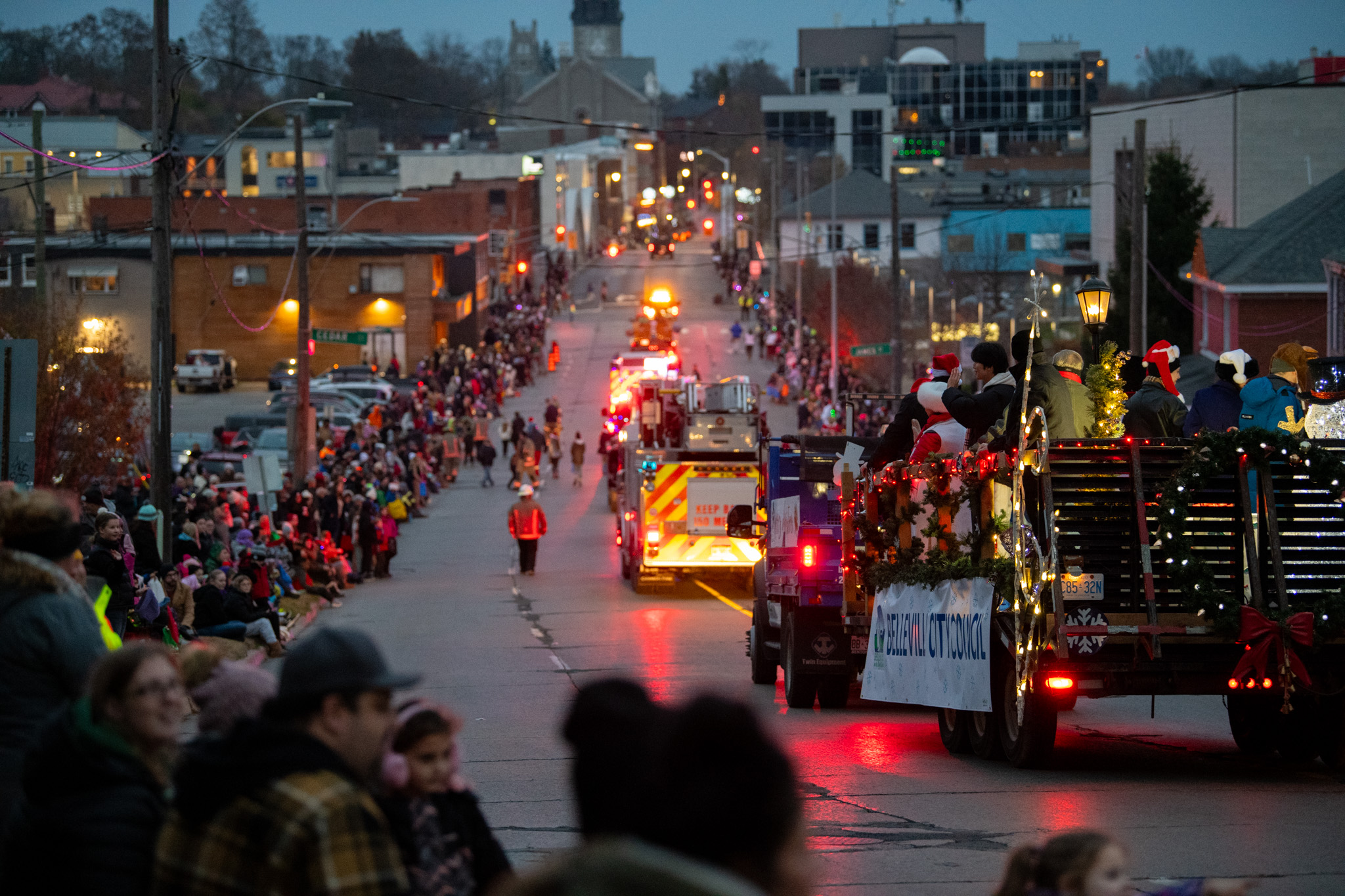 Trucks driving down street with lights during Santa Claus parade