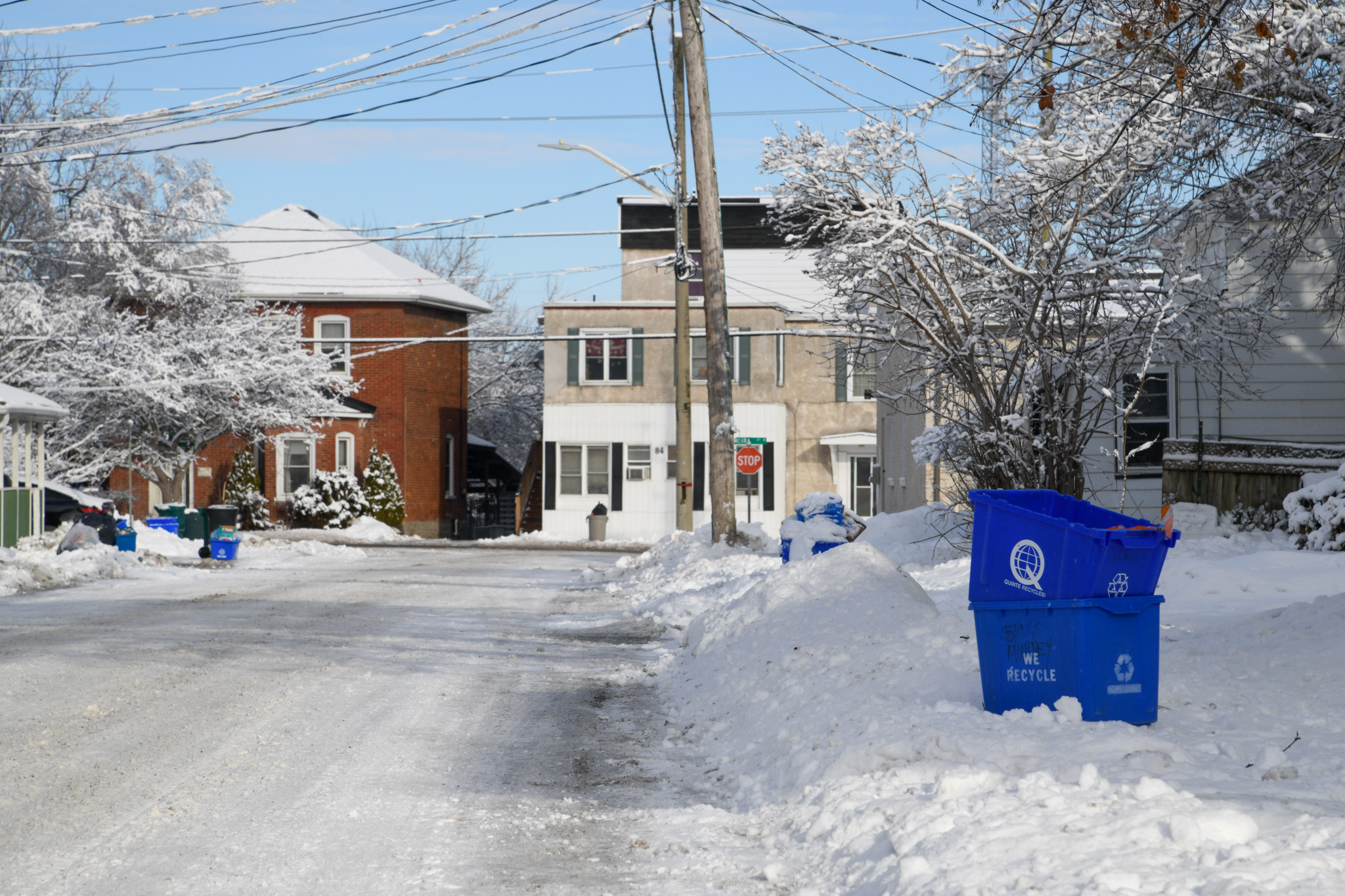 Recycling bin near the curb of a street in winter.